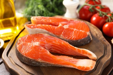 Photo of Board with fresh salmon steaks on table, closeup