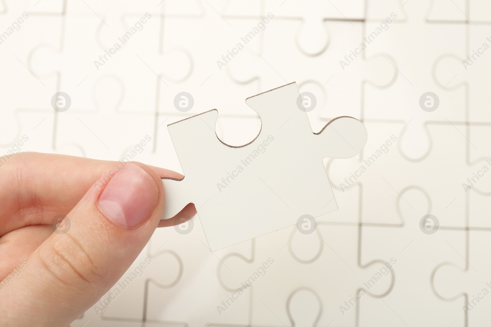 Photo of Woman solving white puzzle, closeup. Logical game