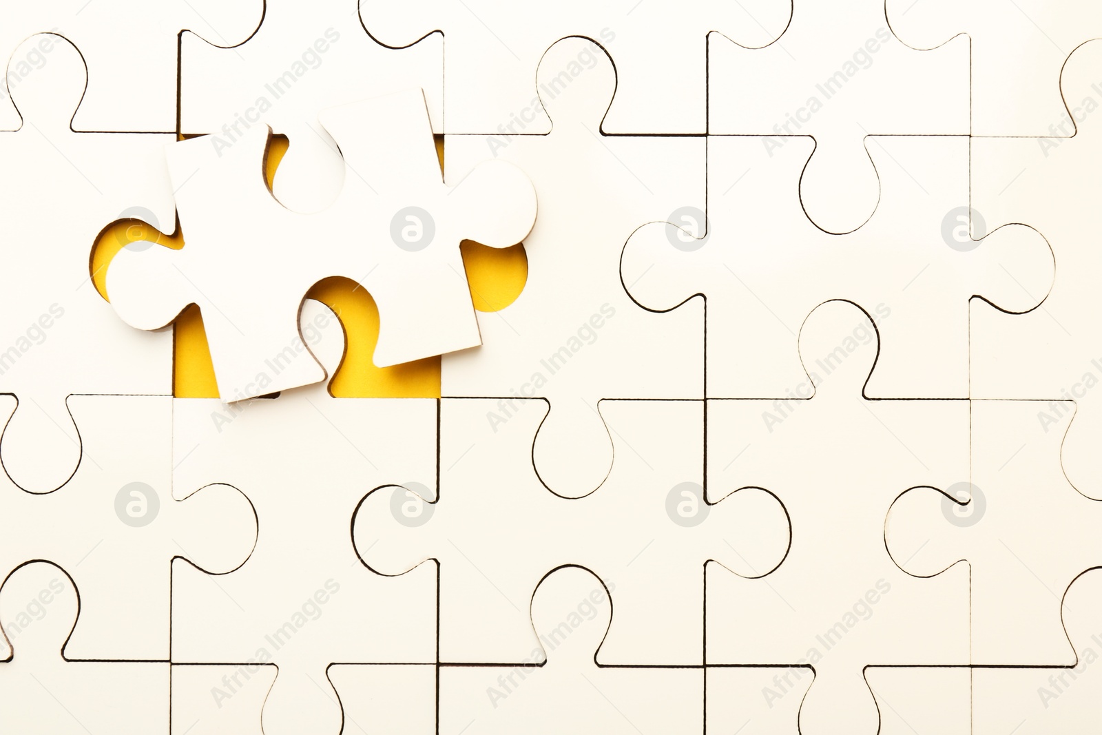 Photo of White puzzle pieces on yellow background, top view