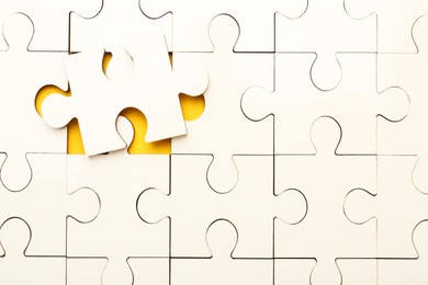 Photo of White puzzle pieces on yellow background, top view