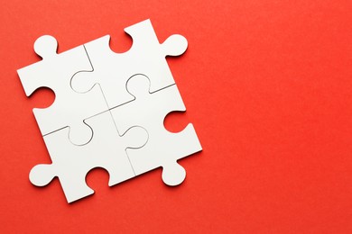 Photo of White puzzle pieces on red background, top view. Space for text