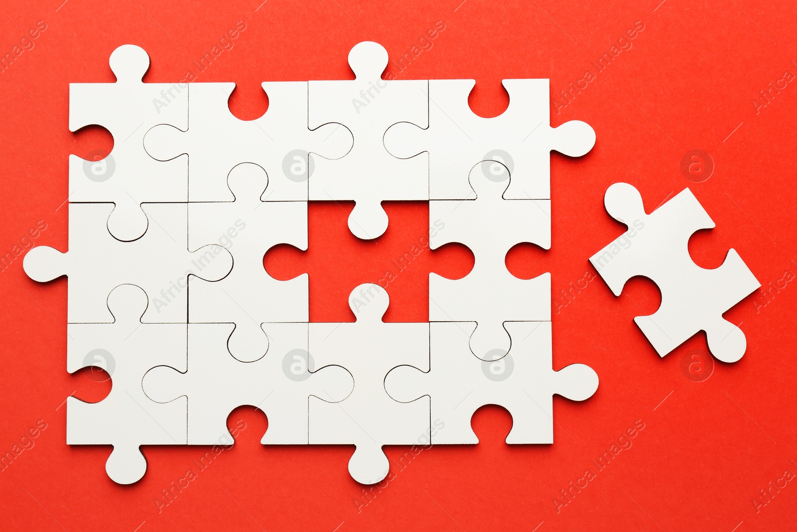 Photo of White puzzle pieces on red background, top view