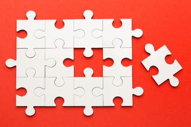 Photo of White puzzle pieces on red background, top view