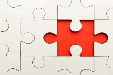 Photo of White puzzle with missing piece on red background, top view