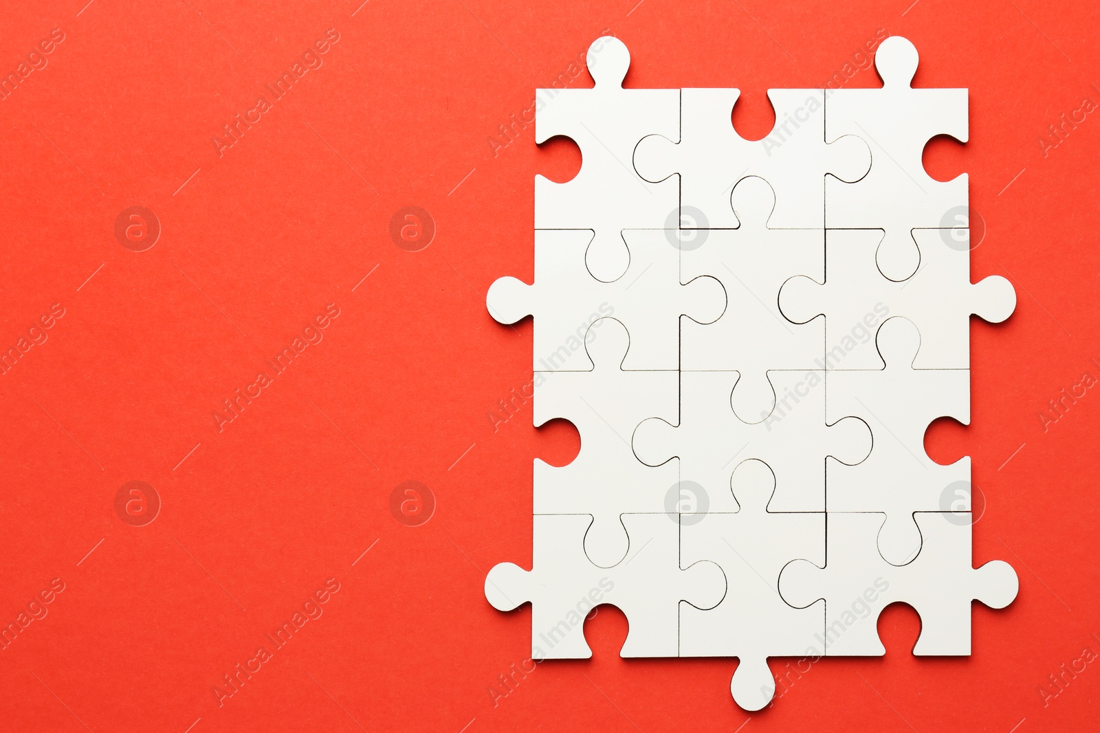 Photo of White puzzle pieces on red background, top view. Space for text