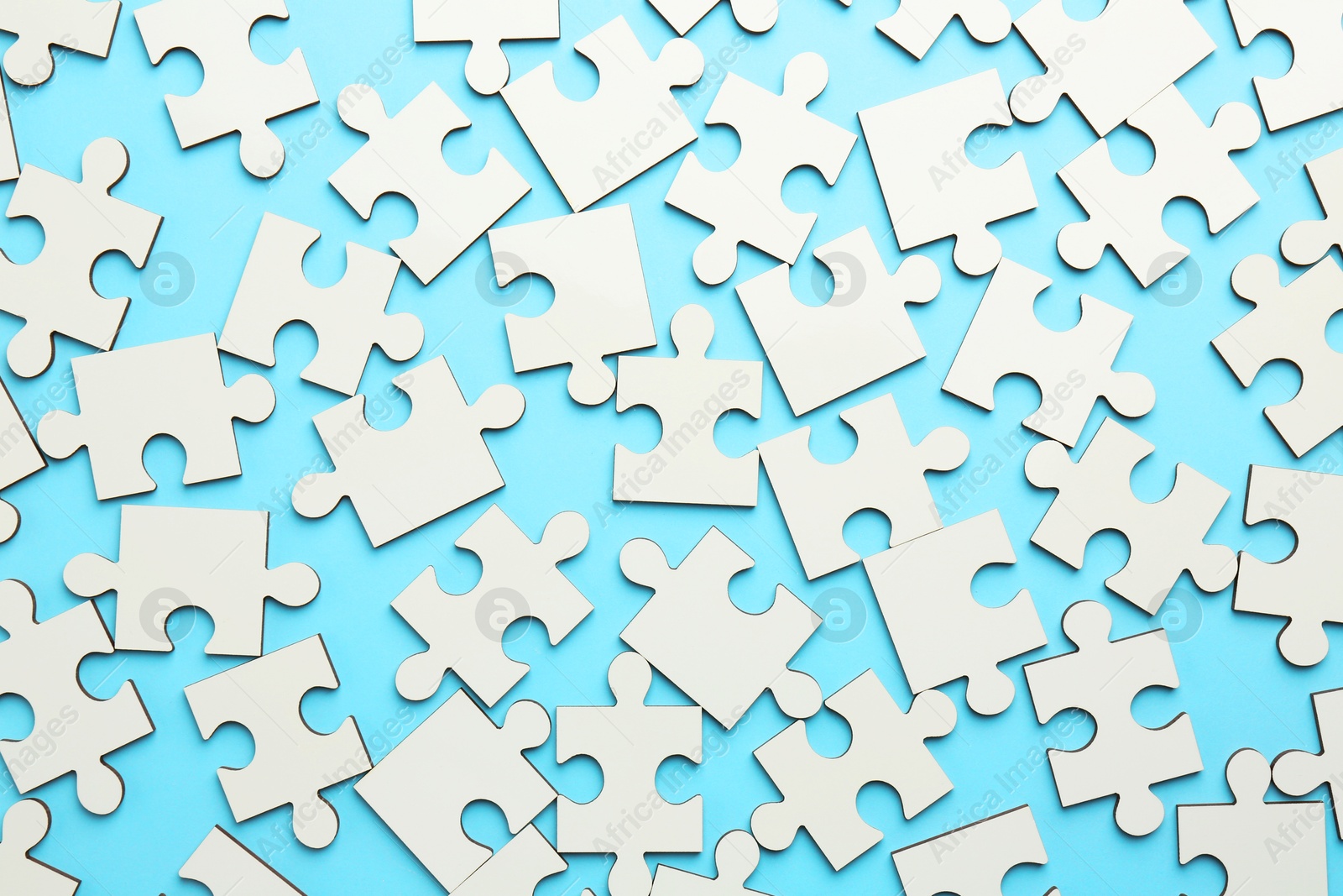 Photo of White puzzle pieces on light blue background, top view