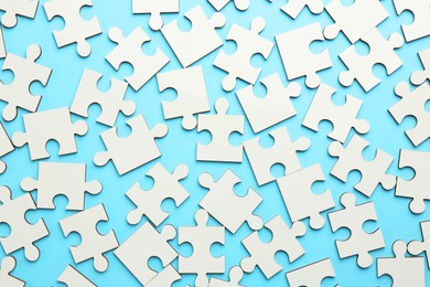 Photo of White puzzle pieces on light blue background, top view