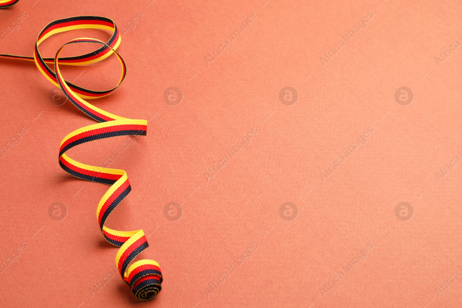 Photo of Ribbon in colors of German flag on color background. Space for text