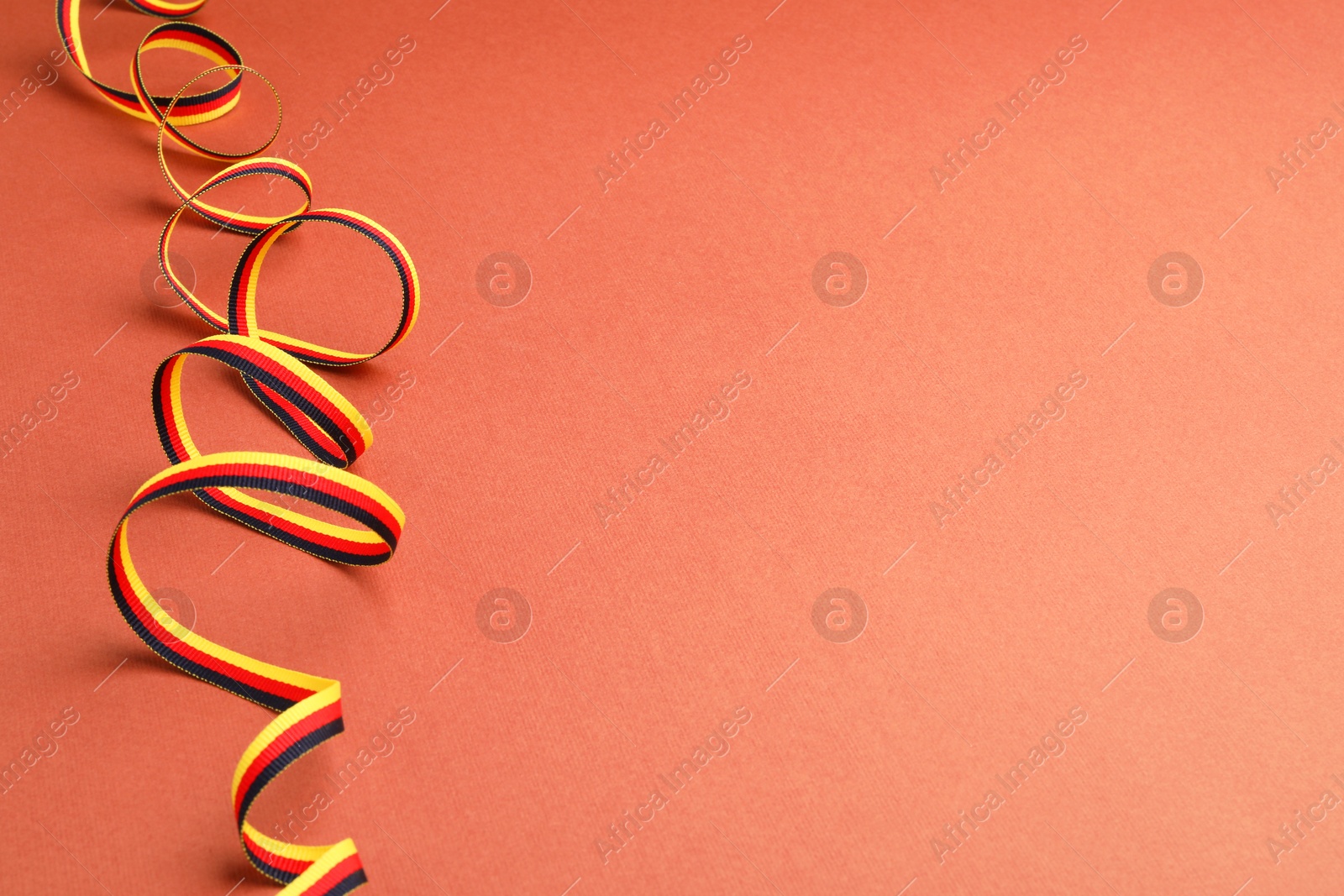 Photo of Ribbon in colors of German flag on color background. Space for text