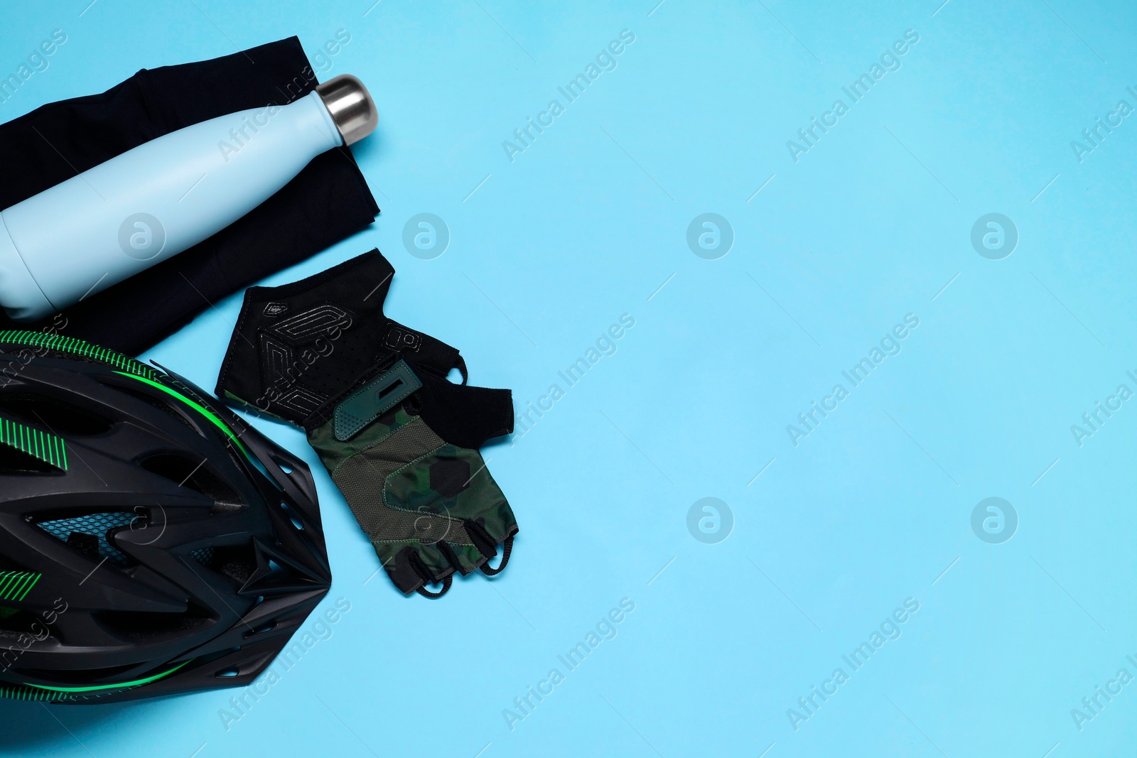 Photo of Bicycle helmet, sportswear and thermo bottle on light blue background, flat lay. Space for text