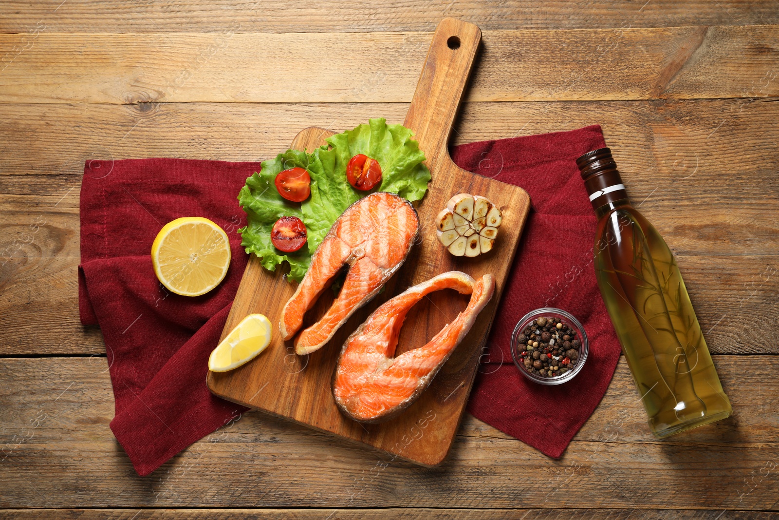 Photo of Tasty grilled salmon steaks, vegetables, spices, oil and lemon on wooden table, flat lay