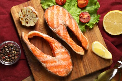 Photo of Tasty grilled salmon steaks, vegetables, spices and lemon on table, flat lay