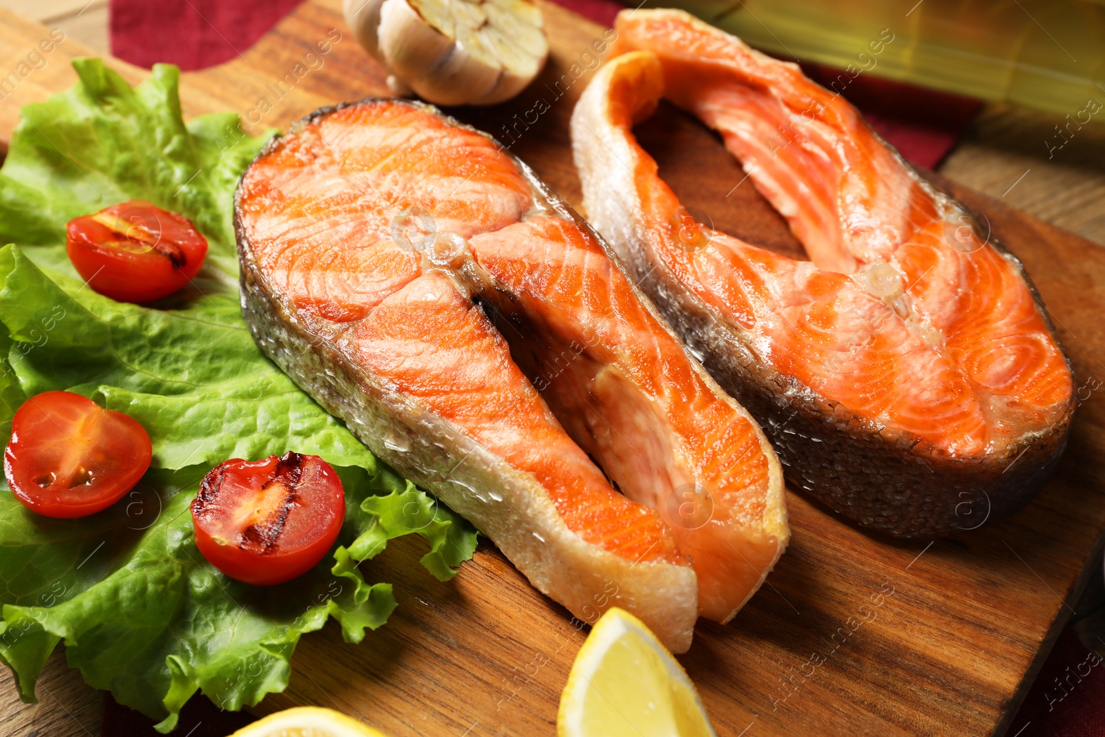 Photo of Tasty grilled salmon steaks and vegetables on table, closeup