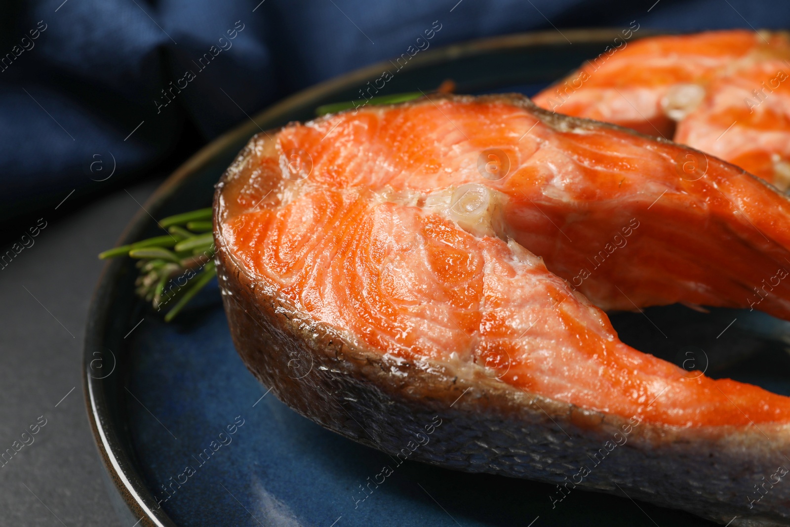 Photo of Tasty grilled salmon steaks on black table, closeup