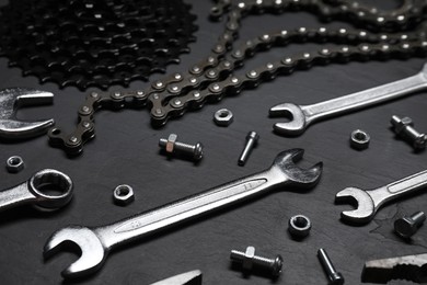 Different bicycle components and tools on dark gray textured background, closeup