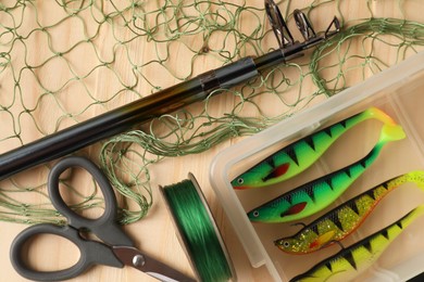 Photo of Fishing rod, baits, line, scissors and net on wooden table, top view