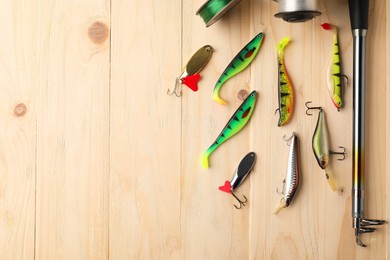 Fishing rod, tackles and line on wooden table, flat lay. Space for text