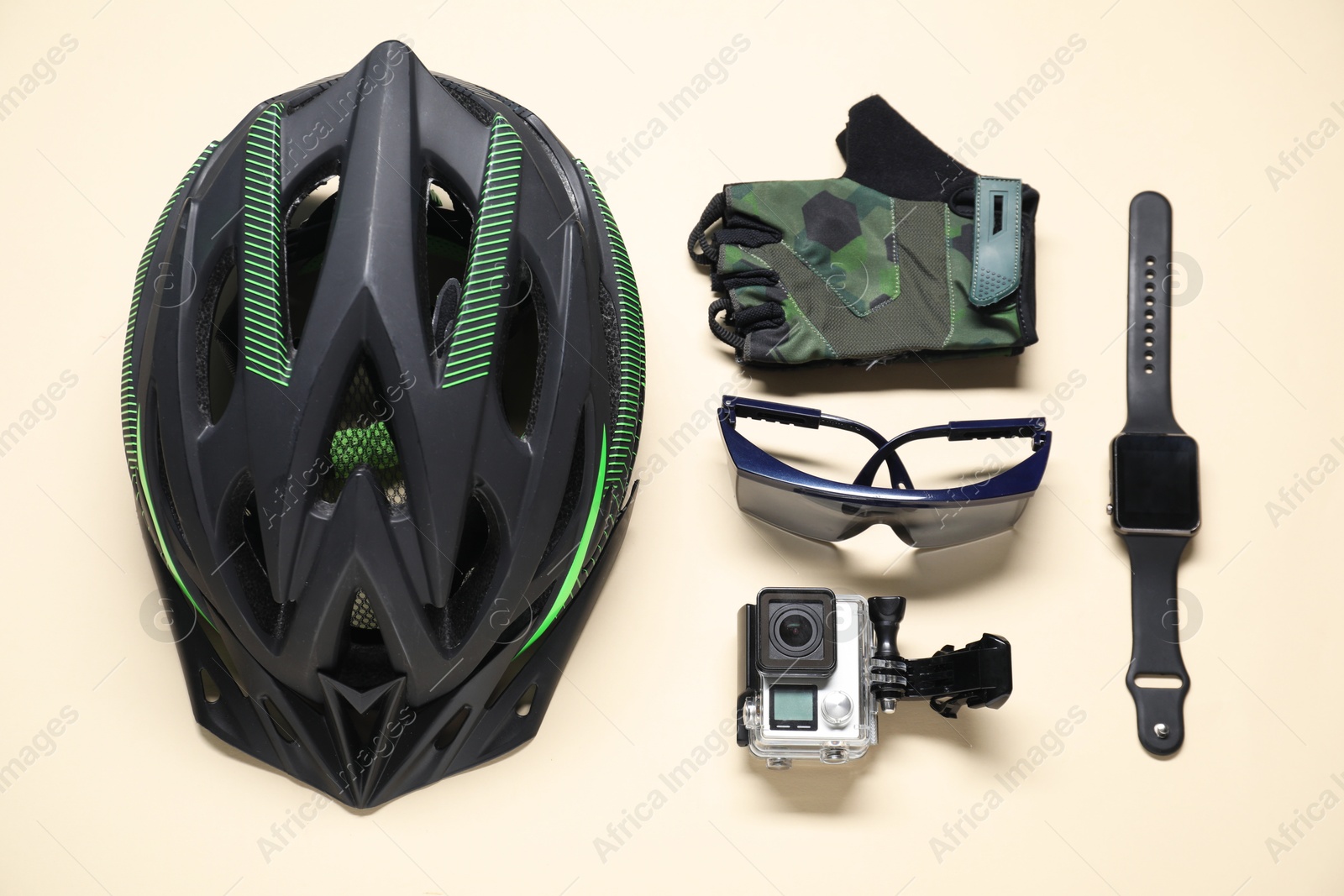 Photo of Bicycle helmet, fingerless cycling gloves, goggles and gadgets on beige background, flat lay