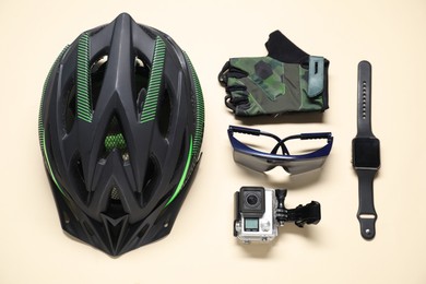 Photo of Bicycle helmet, fingerless cycling gloves, goggles and gadgets on beige background, flat lay