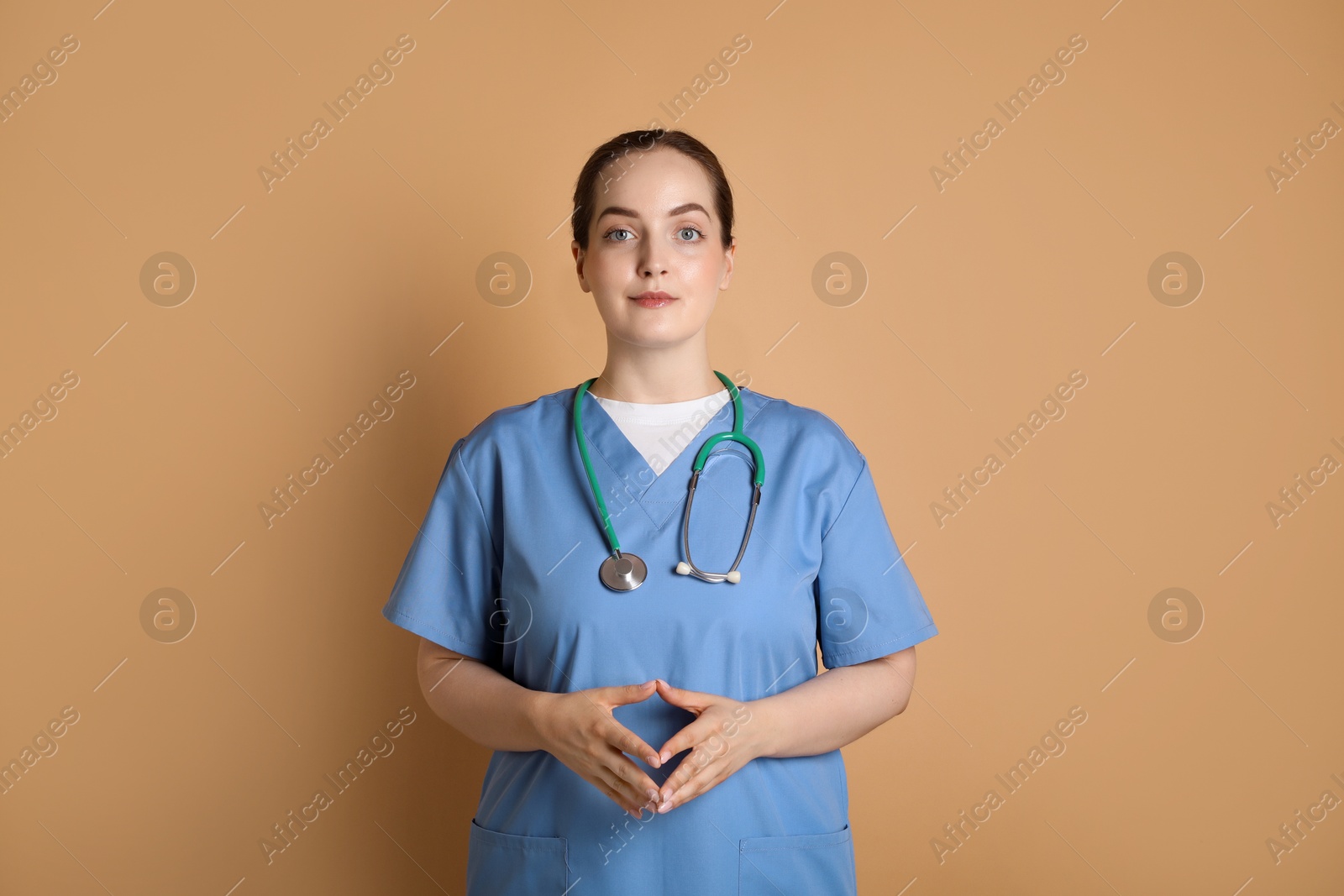 Photo of Portrait of professional nurse with stethoscope on dark beige background