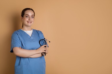 Portrait of professional nurse with stethoscope on dark beige background. Space for text