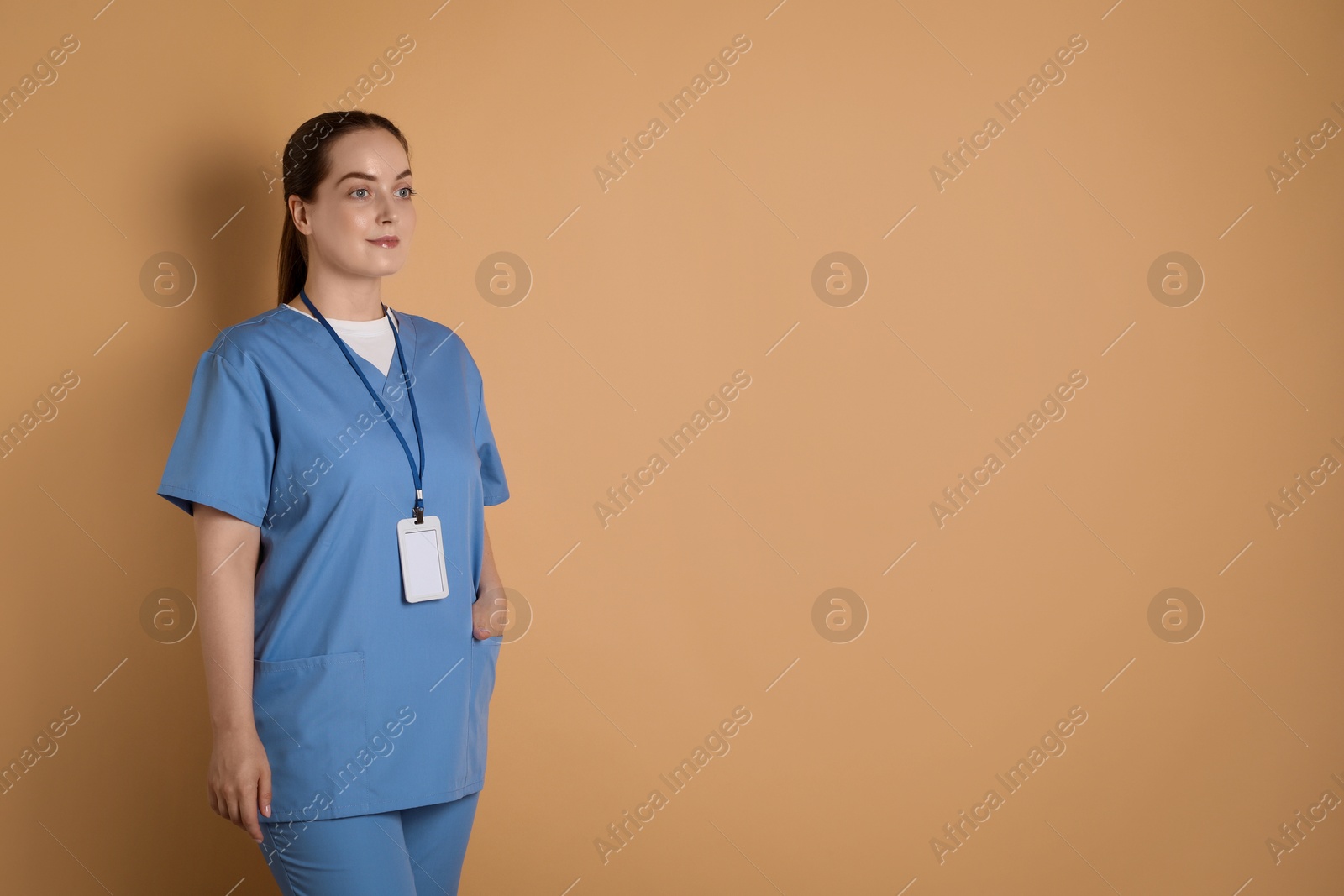 Photo of Professional nurse with badge on dark beige background. Space for text