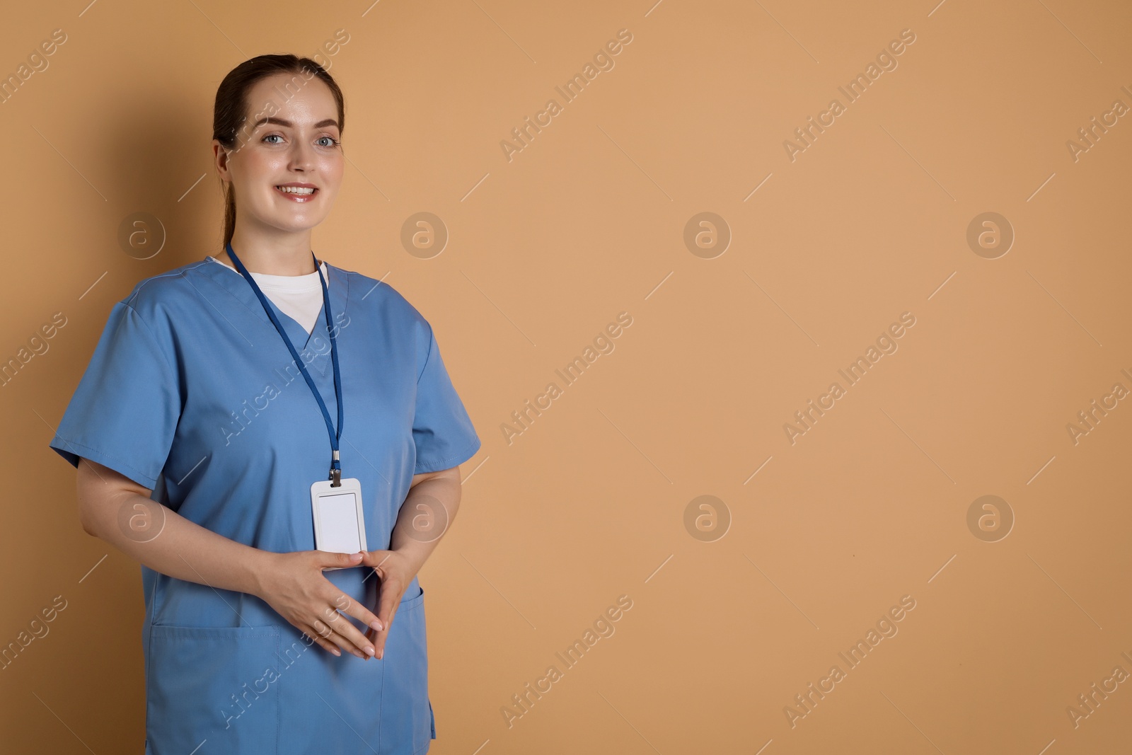 Photo of Professional nurse with badge on dark beige background. Space for text