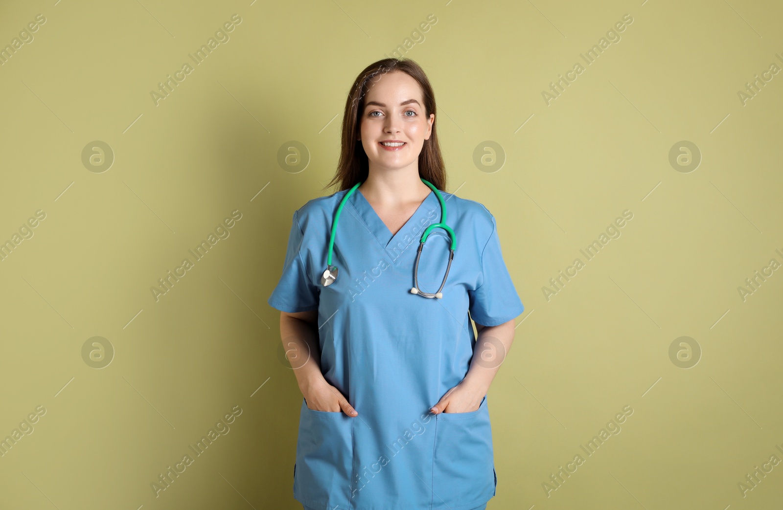 Photo of Professional nurse with stethoscope on pale green background