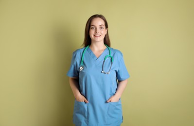 Photo of Professional nurse with stethoscope on pale green background