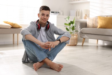 Photo of Full length portrait of teenage boy sitting on floor at home. Space for text