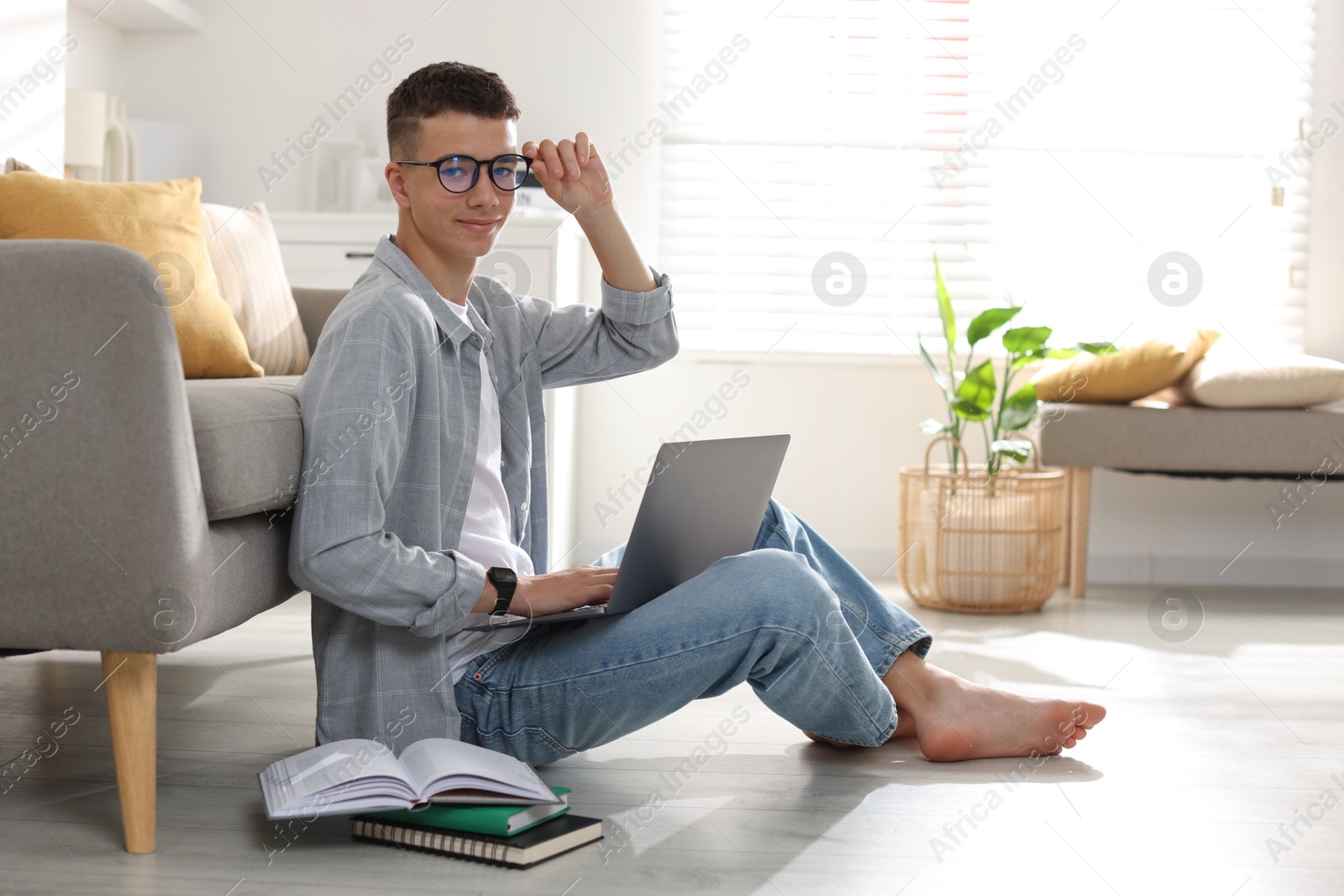 Photo of Full length portrait of teenage boy studying with laptop at home. Space for text