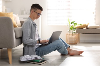 Photo of Full length portrait of teenage boy studying with laptop at home. Space for text