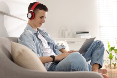 Photo of Teenage boy studying with laptop on sofa at home