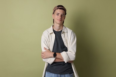 Photo of Portrait of teenage boy with crossed arms on green background