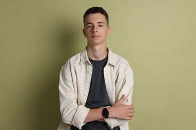 Portrait of teenage boy with crossed arms on green background