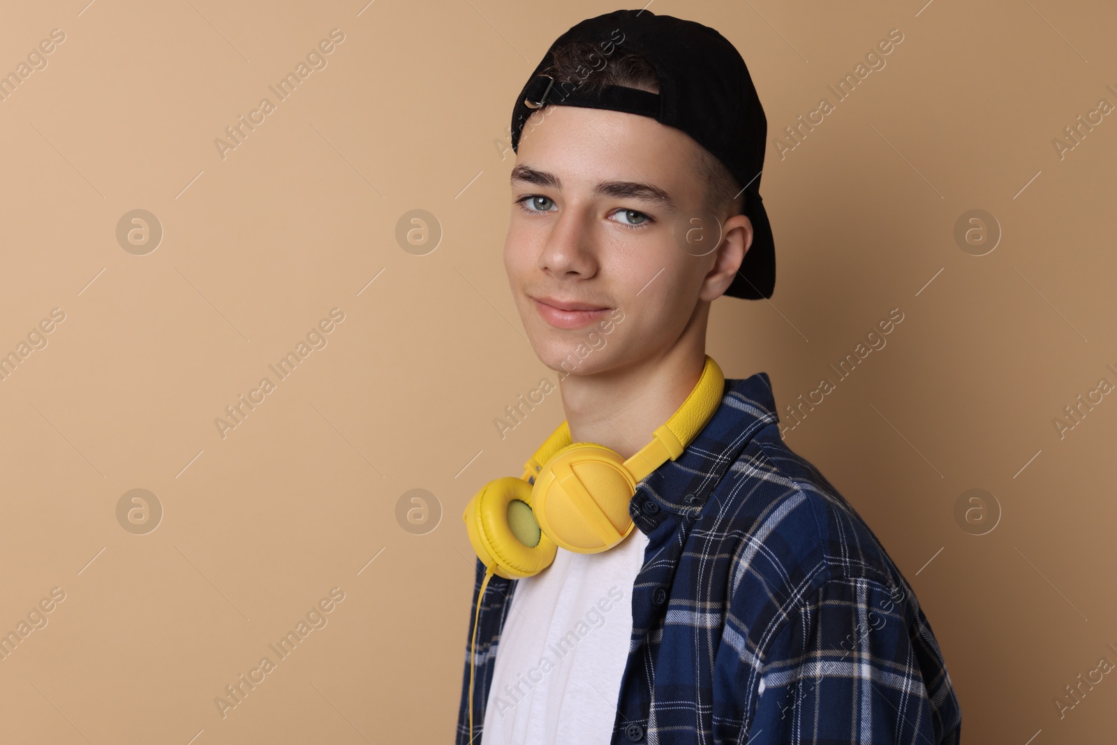 Photo of Portrait of teenage boy on dark beige background. Space for text