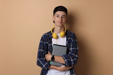 Photo of Portrait of teenage boy with books on dark beige background