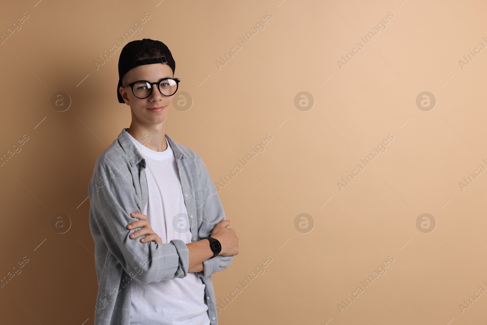 Photo of Portrait of teenage boy with crossed arms on dark beige background. Space for text