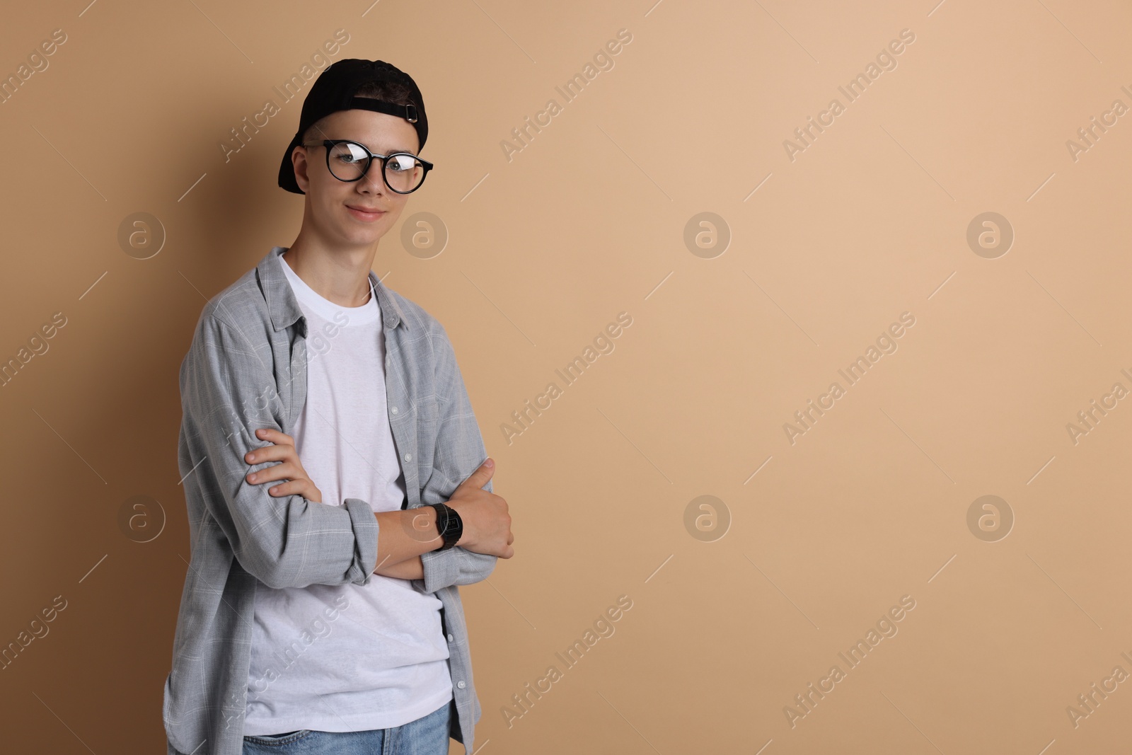 Photo of Portrait of teenage boy with crossed arms on dark beige background. Space for text