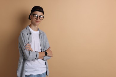 Photo of Portrait of teenage boy with crossed arms on dark beige background. Space for text