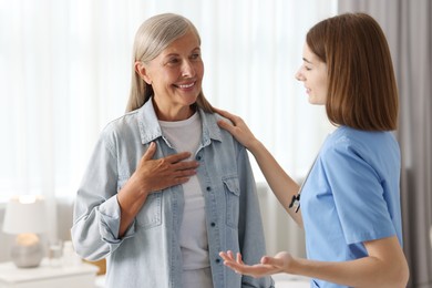 Photo of Young healthcare worker supporting senior patient indoors