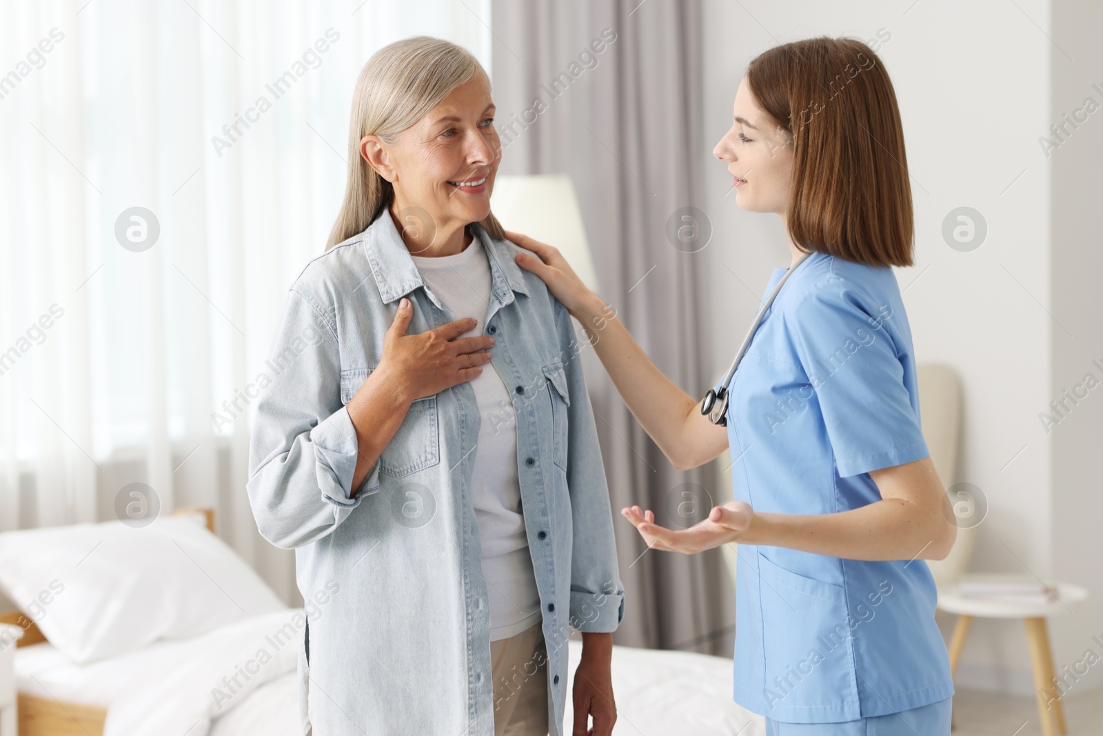 Photo of Young healthcare worker supporting senior patient indoors