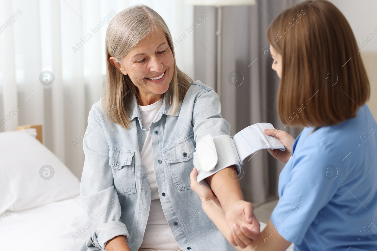 Photo of Healthcare worker measuring patient's blood pressure indoors