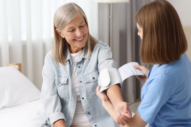 Photo of Healthcare worker measuring patient's blood pressure indoors