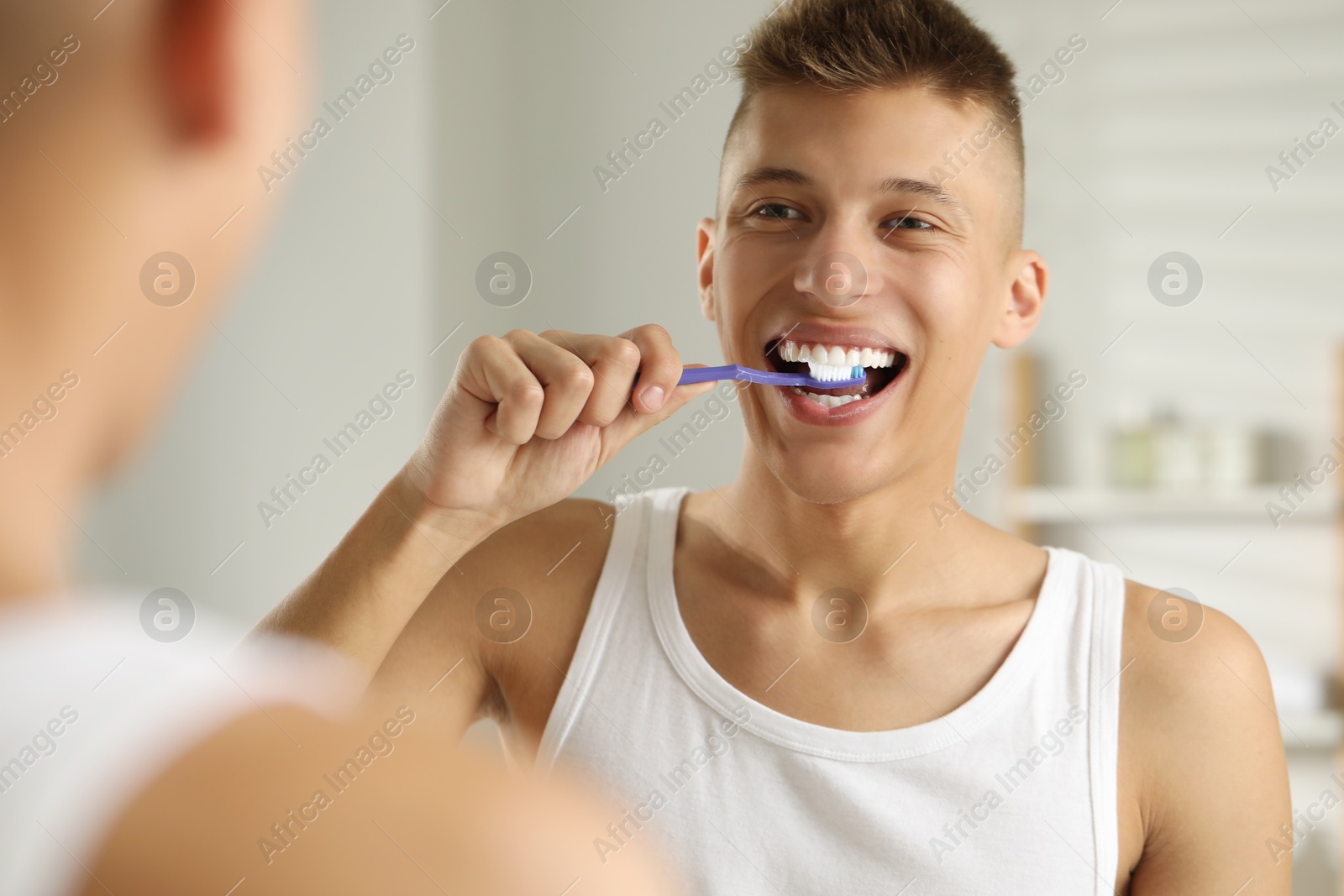 Photo of Young man brushing his teeth in bathroom