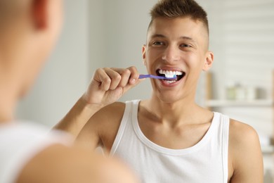 Young man brushing his teeth in bathroom