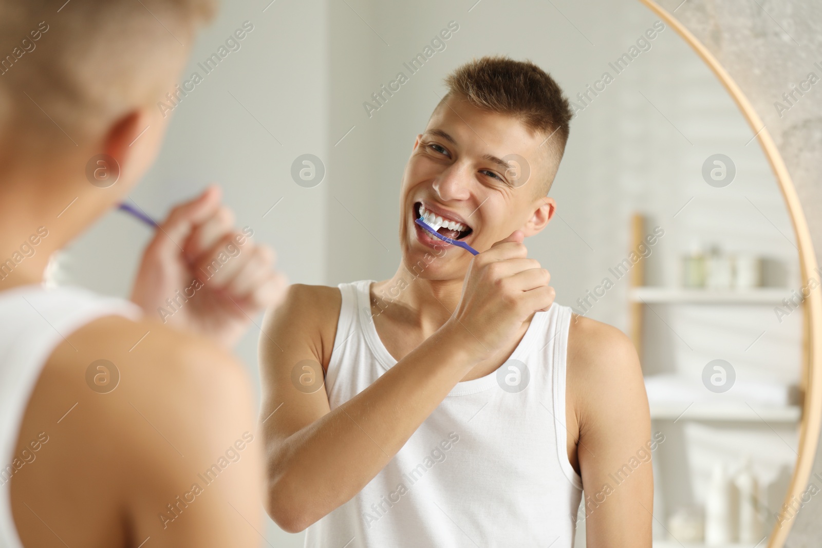 Photo of Young man brushing his teeth in bathroom