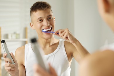 Young man brushing his teeth in bathroom