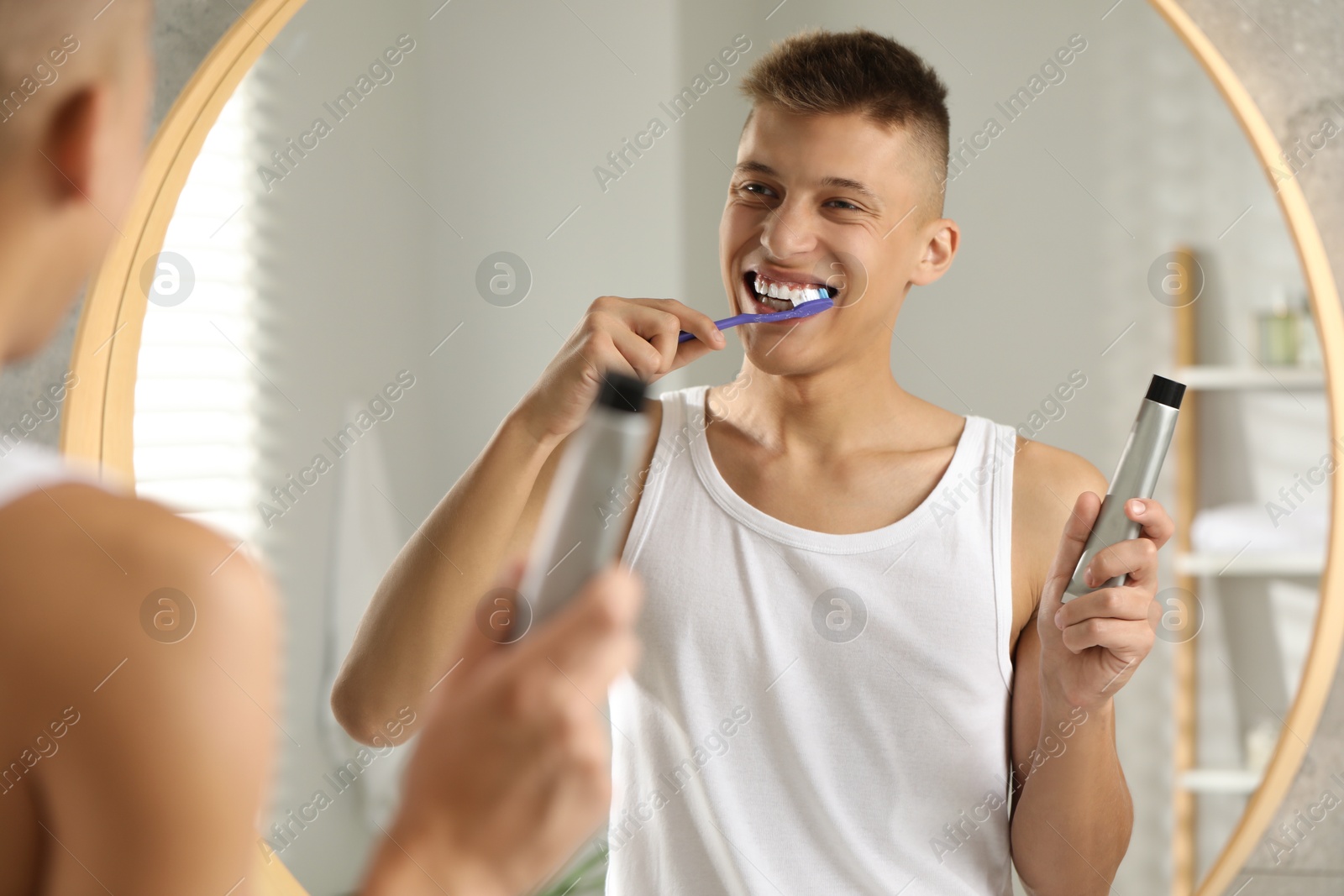 Photo of Young man brushing his teeth in bathroom