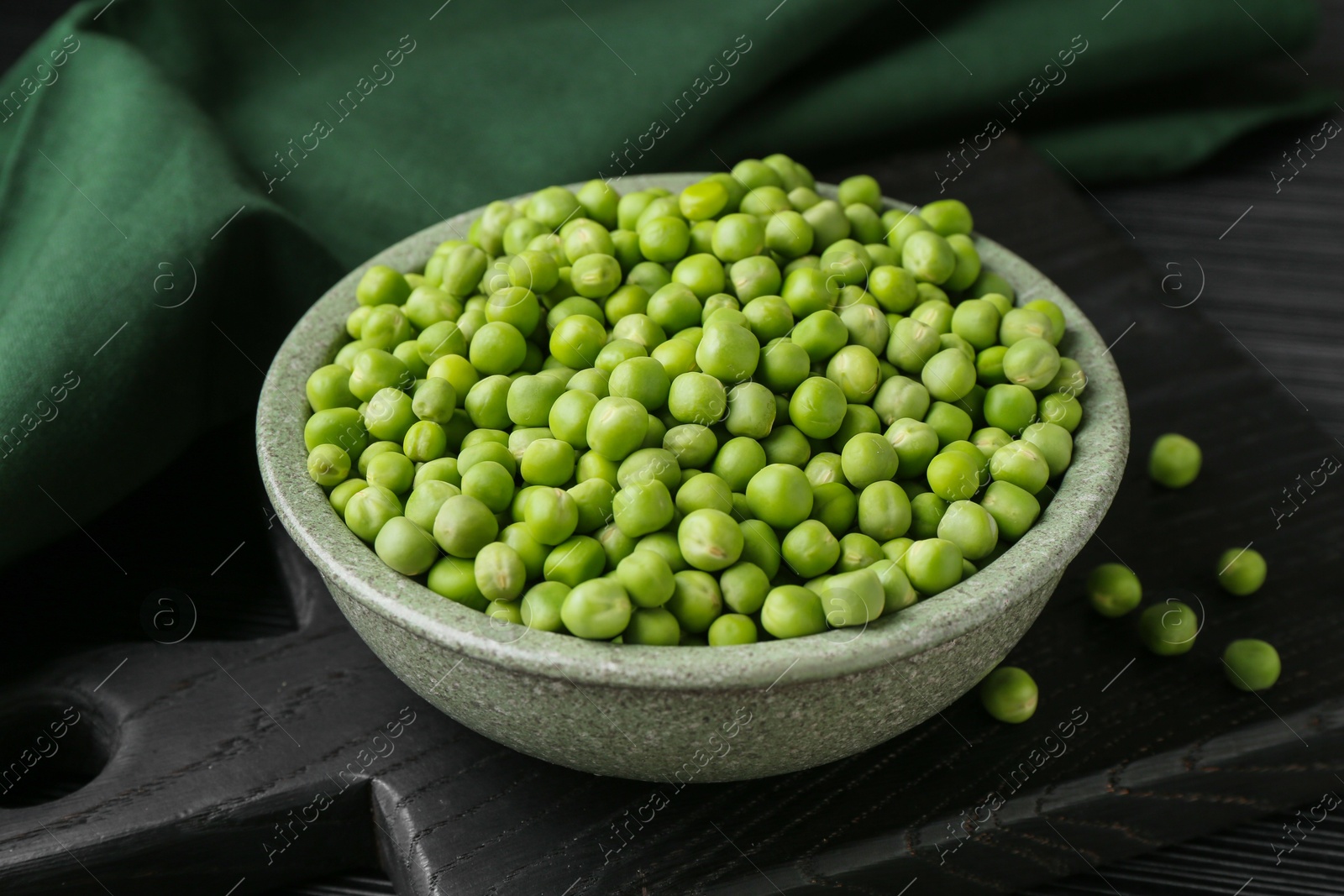 Photo of Fresh green peas in bowl on black wooden table, closeup